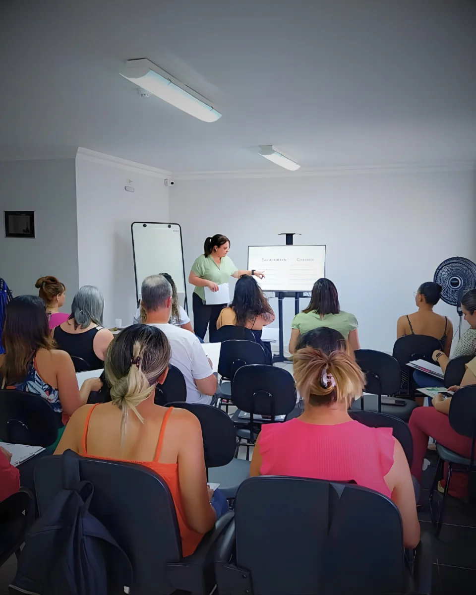 Professora conduzindo uma aula com participantes sentados à sua frente